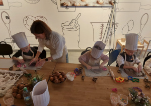 Dzieci wałkują ciasto na pierniczki.