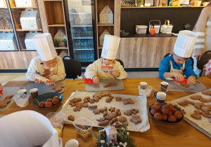 Dzieci wybierają dla siebie upieczone pierniczki.