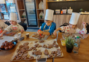 Dzieci dekorują pierniczki lukrem.