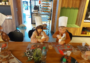 Chłopiec i dziewczynka lukrują pierniczki.