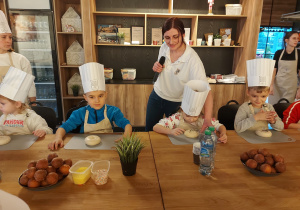 Dzieci siedzą przy bułeczkach.