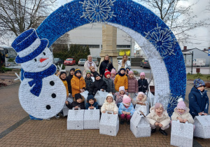 Dzieci pozują do wspólnego zdjęcia pod bombką.