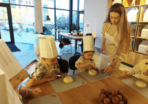 Dzieci posypują kajzerki makiem.