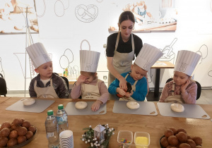 Dzieci zraszją kajzerkę wodą przy pomocy pani.