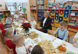 Dzieci siedzą przy stole z panią dyrektor.