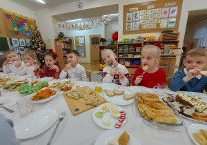 Dzieci siedzą przy stole i jedzą potrawy przygotowane przez rodziców.