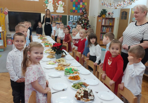 Dzieci stoją przed dzieleniem się opłatkiem.