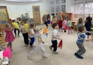 Grupka dzieci biega po sali do muzyki z rekwizytem.