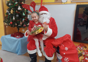 Dziewczynka siedzi na kolanach Mikołaja.