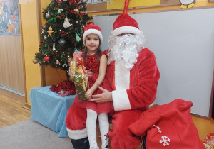 Dziewczynka siedzi na kolanach Mikołaja.