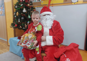 Chłopiec siedzi na kolanach Mikołaja.