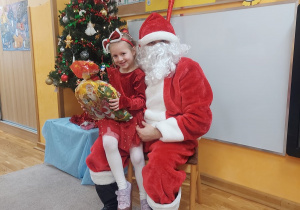 Dziewczynka siedzi na kolanach Świętego Mikołaja.