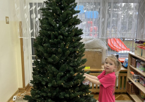 Dziewczynka zawiesza pierwszą bombkę.
