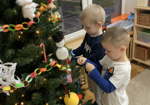 Chłopcy podczas dekorowania choinki.