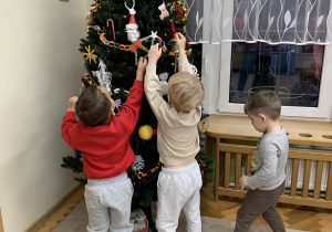 Chłopcy ozdabiają choinkę.
