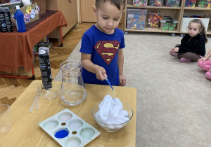 Chłopiec wlewa pepitką niebieską farbę.