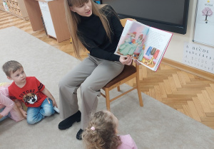 Pani pokazuje dzieciom ilustracje przeczytanej bajki.