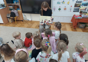Czterolatki oglądają kolorowe ilustracje znajdujące się w książce.