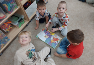 Chłopcy przeglądają książkę o myszkach.