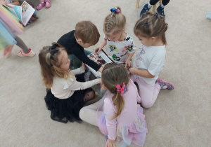 Przedszkolaki z wielkim zainteresowaniem oglądają książki przyniesione z biblioteki.