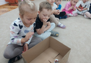 Dziewczynka wkłada kulkę papieru do pudełka.