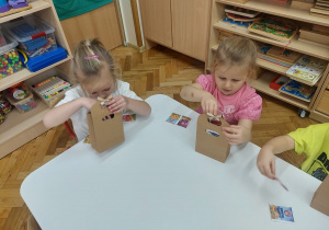 Czterolatki pakują herbatki do pudełek.