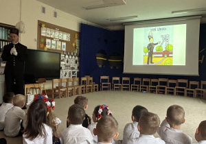 Pan górnik stoi z mikrofonem przed dziećmi.