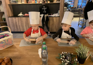 Chłopiec rozwałkowuje ciasto piernikowe.