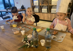 Dziewczynki ozdabiają pierniczki posypkami.