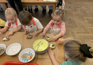 Dziewczynka smaruje lukier na ciasteczko.