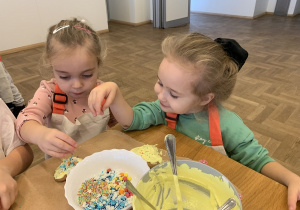 Dziewczynki wybierają posypki na pierniczki.