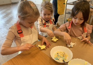 Dziewczynki smarują ciasteczka lukrem.