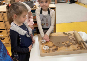 Dziewczynka za pomocą foremki nadaje kształt pierniczkowi.