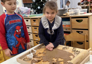 Dziewczynka za pomocą foremki nadaje kształt pierniczkowi.