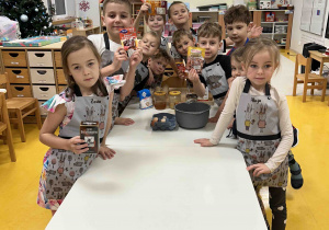 Dzieci w fartuszkach czekają na rozpoczęcie zajęć kulinarnych.