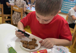 Chłopiec dekoruje lukrem pierniczka.