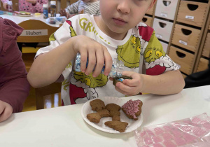 Chłopiec sypie posypkę na pierniczka.