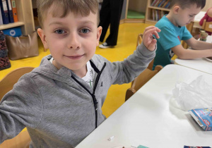 Zadowolony chłopczyk dekoruje pierniczki.