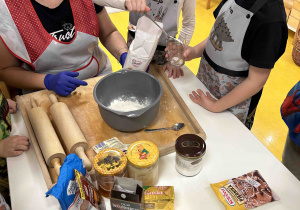 Dziewczynka nasypuje mąkę do szklanki.