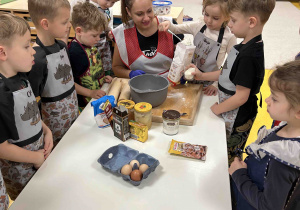 Dzieci wraz z panią wsypują składniki według przepisu.