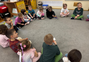 Dzieci siedzą w kole.
