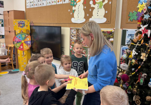 Dzieci wręczają mamie Piotrusia podziękowanie ze swoimi rysunkami.