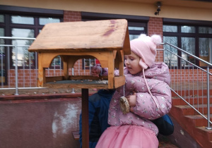 16 Dziewczynka sypie ziarenka do karmnika