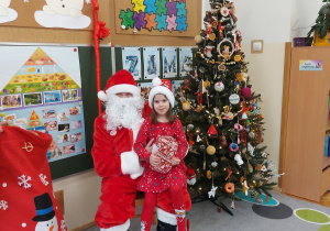 Dziewczynka siedzi z prezentem u mikołaja na kolanach