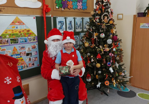 Chłopiec stoi z prezentem przed mikołajem