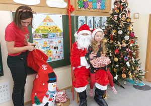 Dziewczynka siedzi z prezentem u mikołaja na kolanach