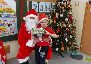 Chłopiec stoi z prezentem przed mikołajem