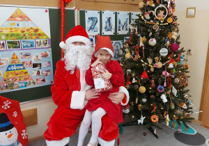 Dziewczynka siedzi z prezentem u mikołaja na kolanach