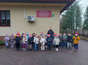Dzieci z kijkami stoją na tle budynku przedszkola.