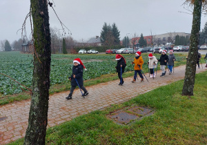 Dzieci idą chodnikiem z kijkami